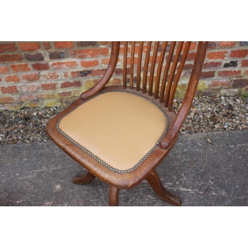 555 - A 1920s oak vertical rail back office chair, on quadruple splay support