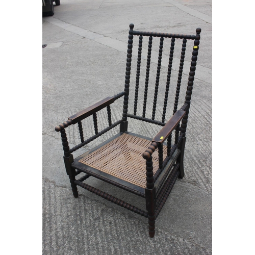 513 - A 19th century bobbin turned fruitwood elbow chair with cane seat, on turned and stretchered support... 