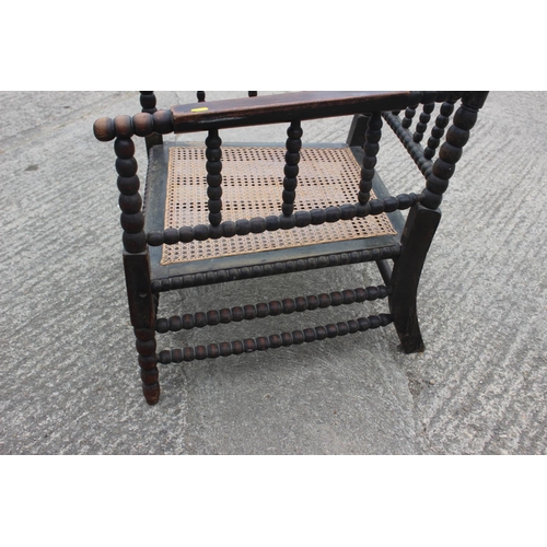 513 - A 19th century bobbin turned fruitwood elbow chair with cane seat, on turned and stretchered support... 