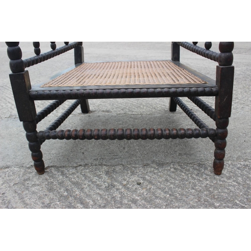 513 - A 19th century bobbin turned fruitwood elbow chair with cane seat, on turned and stretchered support... 