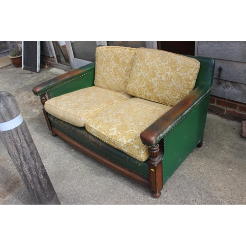 519 - A 1930s oak two-seat settee, upholstered in a green leather, 54