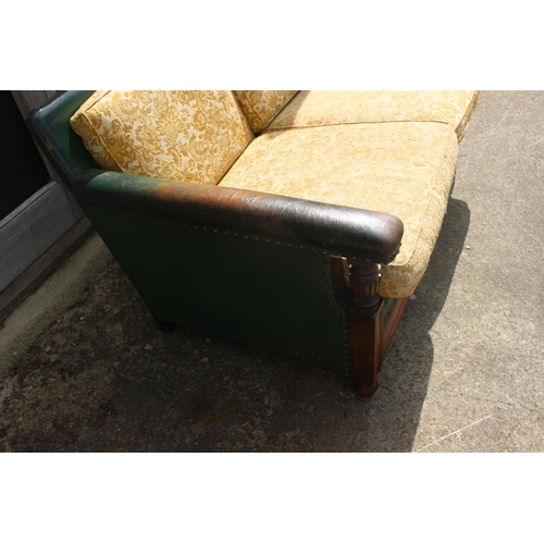 519 - A 1930s oak two-seat settee, upholstered in a green leather, 54