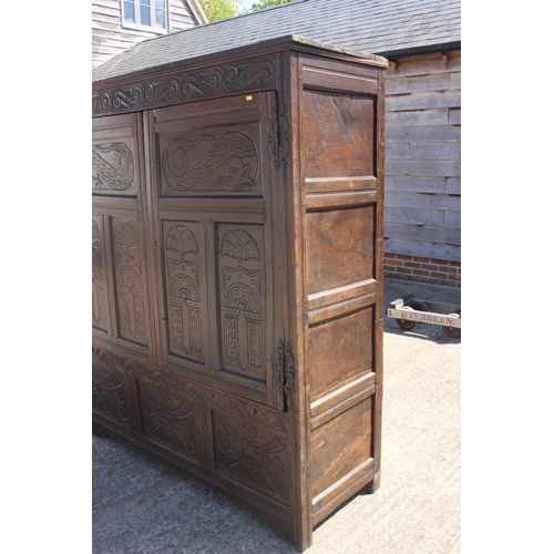 527 - An 18th century carved oak wardrobe enclosed two panelled doors with serpent hinges, on stile suppor... 