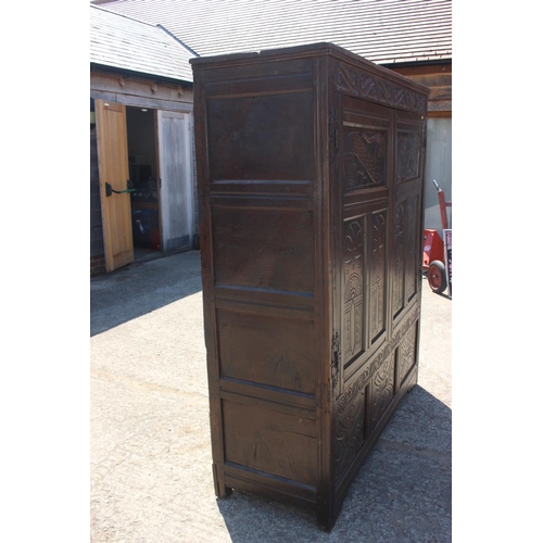 527 - An 18th century carved oak wardrobe enclosed two panelled doors with serpent hinges, on stile suppor... 