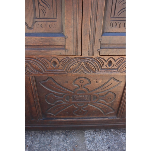 527 - An 18th century carved oak wardrobe enclosed two panelled doors with serpent hinges, on stile suppor... 