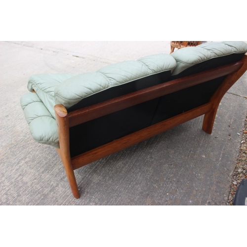 550 - A 1970s teak frame two-seat settee, upholstered in a sage green leather with loose seat and back cus... 