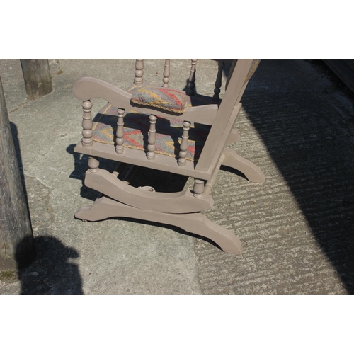 610 - An early 20th century American style grey painted rocking chair, upholstered in a zig-zag fabric