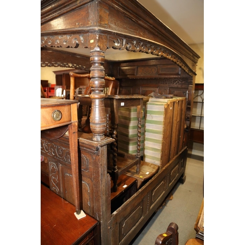 484 - A 17th century carved oak fourposter bed with panelled back, fitting sliding cupboard and inscriptio... 