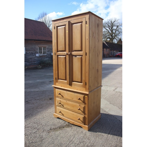 540 - A waxed pine wardrobe, the upper section enclosed two panelled doors over three drawers, on bracket ... 