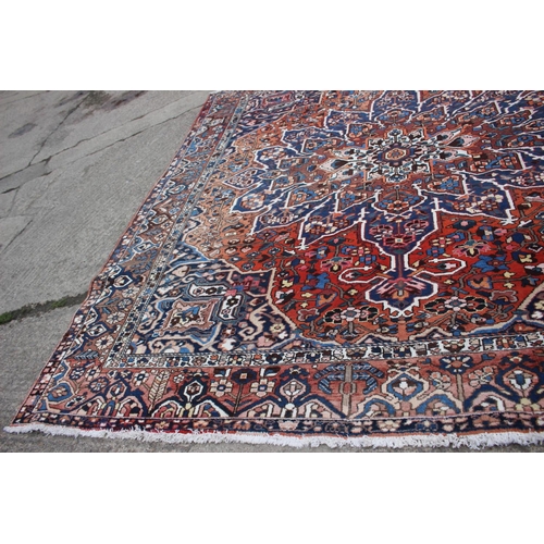 548 - A Hamadan carpet with central star design, on a salmon ground, in shades of blue, brown, pink, orang... 