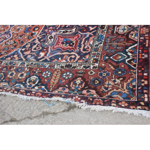 548 - A Hamadan carpet with central star design, on a salmon ground, in shades of blue, brown, pink, orang... 