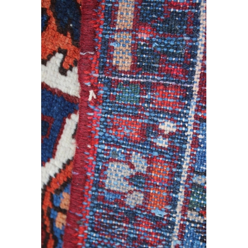 548 - A Hamadan carpet with central star design, on a salmon ground, in shades of blue, brown, pink, orang... 