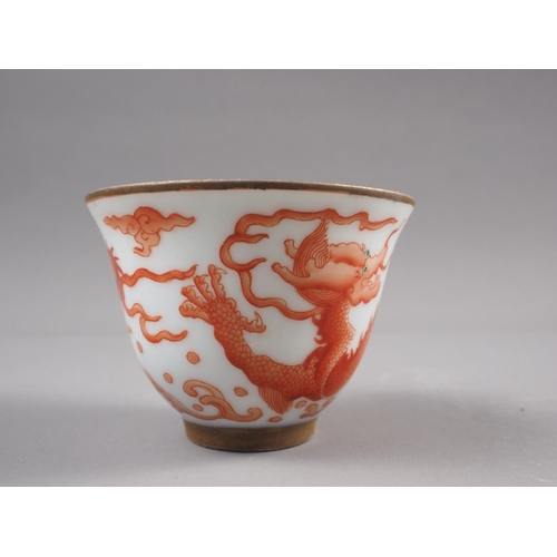 78 - A pair of Chinese iron red and white glazed tea bowls and saucers, decorated dragons and flaming pea... 