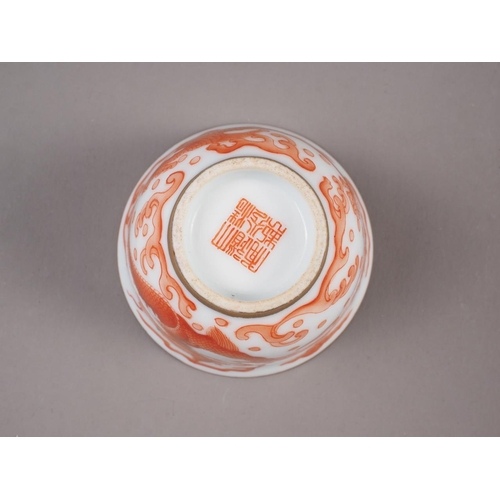 78 - A pair of Chinese iron red and white glazed tea bowls and saucers, decorated dragons and flaming pea... 