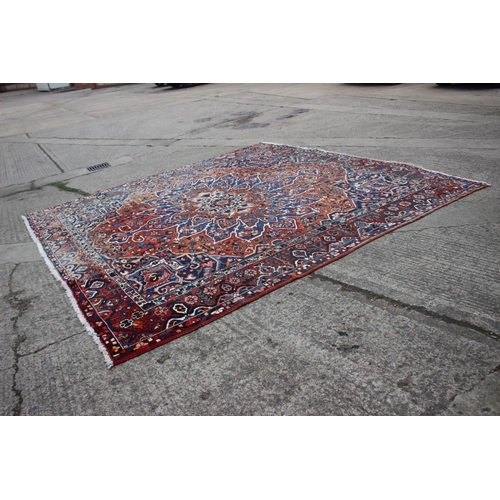 548 - A Hamadan carpet with central star design, on a salmon ground, in shades of blue, brown, pink, orang... 