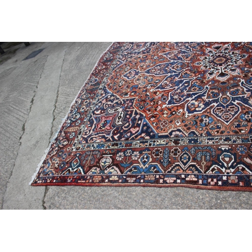 548 - A Hamadan carpet with central star design, on a salmon ground, in shades of blue, brown, pink, orang... 