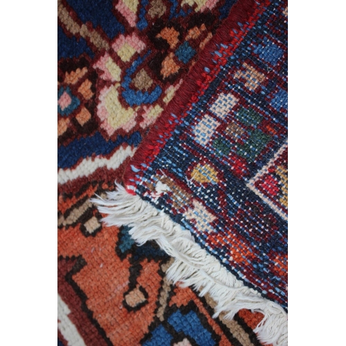 548 - A Hamadan carpet with central star design, on a salmon ground, in shades of blue, brown, pink, orang... 