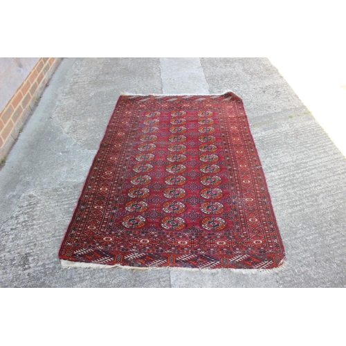 541 - A Bokhara rug with thirty-three guls on a red ground with multi-borders in shades of green, orange a... 