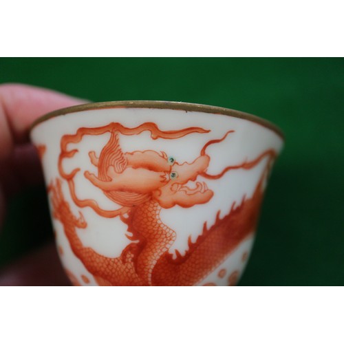 78 - A pair of Chinese iron red and white glazed tea bowls and saucers, decorated dragons and flaming pea... 