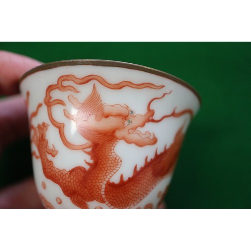 78 - A pair of Chinese iron red and white glazed tea bowls and saucers, decorated dragons and flaming pea... 