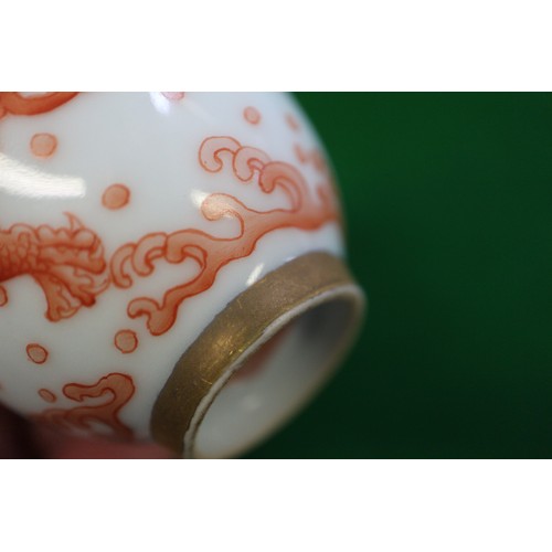 78 - A pair of Chinese iron red and white glazed tea bowls and saucers, decorated dragons and flaming pea... 