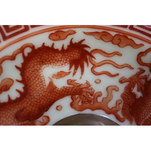 78 - A pair of Chinese iron red and white glazed tea bowls and saucers, decorated dragons and flaming pea... 