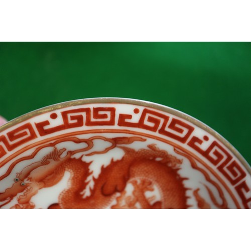 78 - A pair of Chinese iron red and white glazed tea bowls and saucers, decorated dragons and flaming pea... 