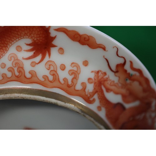 78 - A pair of Chinese iron red and white glazed tea bowls and saucers, decorated dragons and flaming pea... 