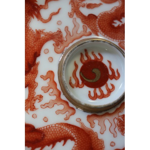 78 - A pair of Chinese iron red and white glazed tea bowls and saucers, decorated dragons and flaming pea... 