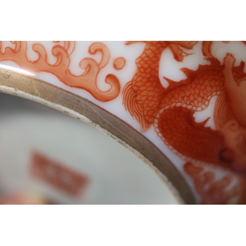 78 - A pair of Chinese iron red and white glazed tea bowls and saucers, decorated dragons and flaming pea... 