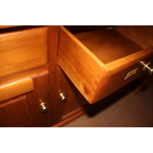 538 - A Ducal pine dresser, the upper section enclosed three glazed panel doors over three drawers and cup... 