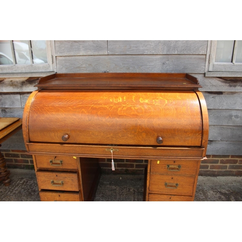 427 - An Edwardian oak cylinder top double pedestal desk with fitted interior over six graduated drawers, ... 