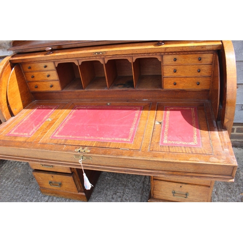 427 - An Edwardian oak cylinder top double pedestal desk with fitted interior over six graduated drawers, ... 