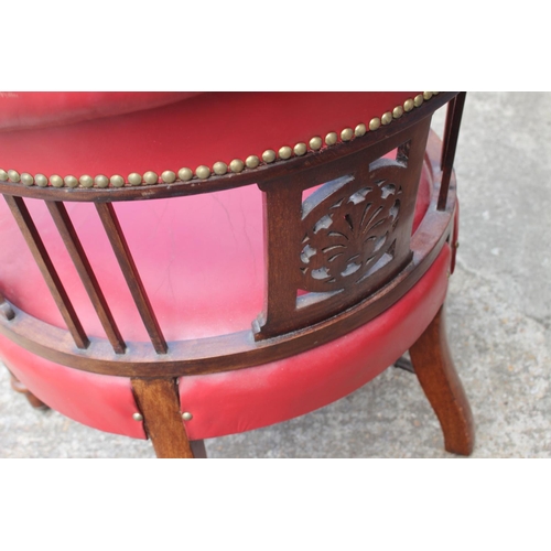 498 - An oak and red studded leather tub chair with pierced splats, fluted supports and crinoline stretche... 