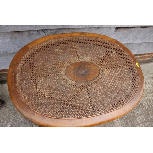 502 - A mahogany oval occasional table with rattan top, on barley twist supports united by an 'X' stretche... 