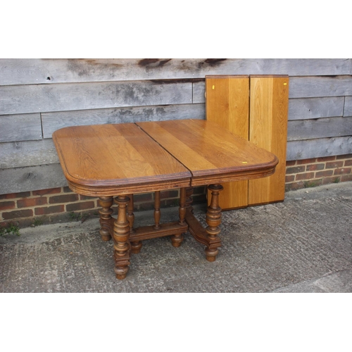 544 - A French light oak extending dining table with two extra leaves, on turned supports and shaped base,... 