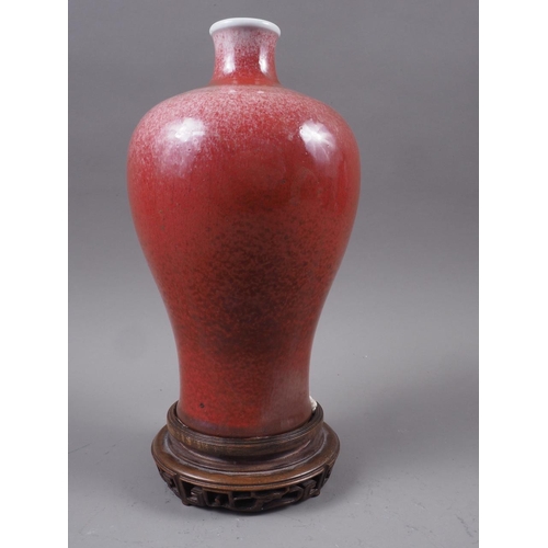 69 - A Chinese meiping red glazed vase, on hardwood stand, 10 3/4