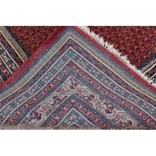 456 - A Persian carpet with all-over boteh design on a red ground, multi-bordered in shades of blue, red, ... 