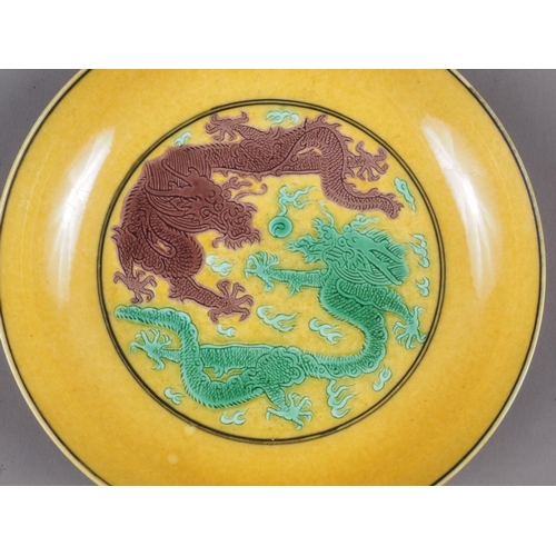 72 - A Chinese yellow glazed dish with two dragons and reverse decorated with grapes, seal mark to base, ... 