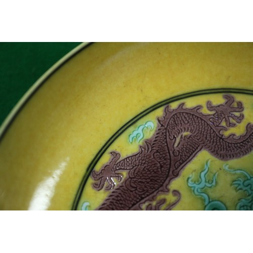 72 - A Chinese yellow glazed dish with two dragons and reverse decorated with grapes, seal mark to base, ... 