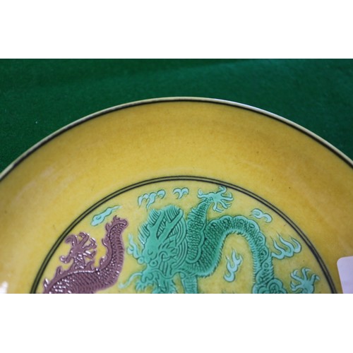 72 - A Chinese yellow glazed dish with two dragons and reverse decorated with grapes, seal mark to base, ... 