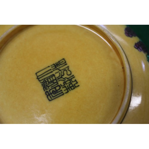 72 - A Chinese yellow glazed dish with two dragons and reverse decorated with grapes, seal mark to base, ... 