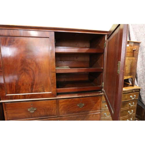 412 - An early 19th century mahogany linen press, the upper section fitted trays enclosed two doors, over ... 