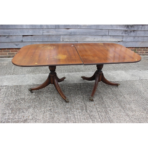 509 - A mahogany double pedestal dining table with extra leaf, on twin turned columns and tripod splay sup... 