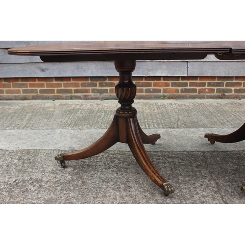 509 - A mahogany double pedestal dining table with extra leaf, on twin turned columns and tripod splay sup... 