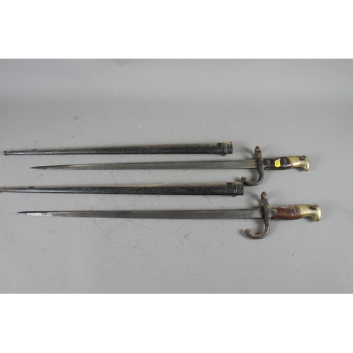 157 - Two late 19th century French epee bayonets, in metal scabbards, 20 1/2