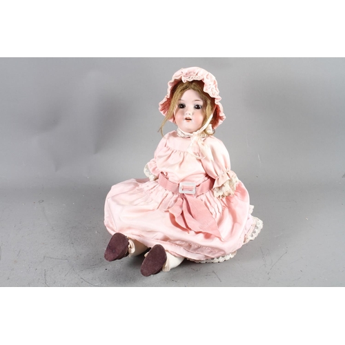 159 - An Armand & Marseille bisque headed doll, in a pink dress and bonnet, a wicker chair and a wicker wa... 