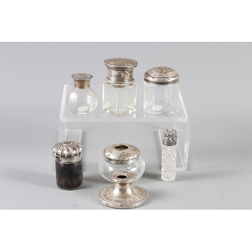 236 - A silver topped salts bottle, a silver topped cut glass scent bottle, four other silver topped toile... 