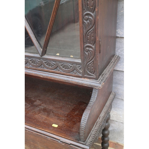 404 - A late 19th century carved oak side cabinet, the upper section enclosed glazed doors, over drop leaf... 