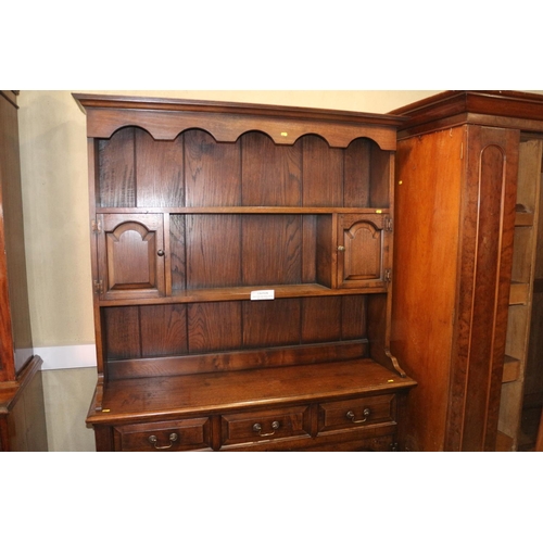 486 - An oak dresser, the upper section fitted two cupboards and open shelves, over three drawers and cupb... 